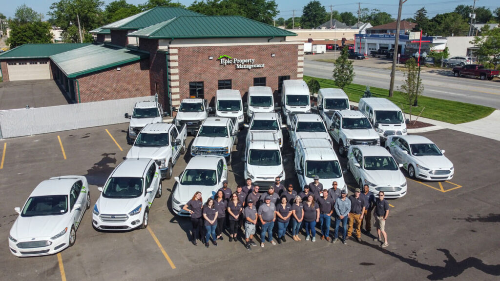 A property management team in the Detroit area stands in front of their offices and vehicle fleet that they use to service rental properties