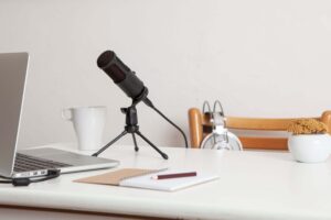 Real estate investing podcasts are represented by a microphone headphones and computer